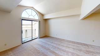 A living room with a cathedral ceiling and a slider to a balcony at South Bridge Apartments, Fort Wayne, Indiana