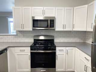 a kitchen with white cabinets and a stainless steel stove and microwave at Stoney Pointe Apartment Homes, Wichita