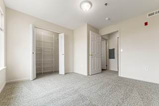 A bedroom with a carpeted floor and a walk-in closet with organizers at Stoney Pointe Apartment Homes, Kansas