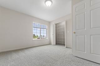 A bedroom with a large window, walk-in closet, and a carpeted floor at Stoney Pointe Apartment Homes, Kansas