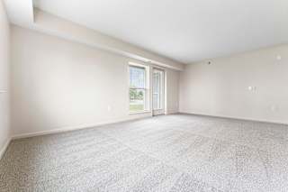 An enlarged living room with a carpeted floor and a french door leading outside to a patio at Stoney Pointe Apartment Homes, Kansas