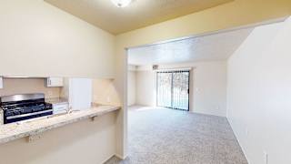 an empty living room and kitchen with a door to the patio  at Swiss Valley Apartments, Wyoming, Michigan