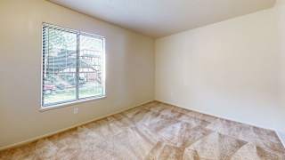 an empty bedroom with a window and carpeting at Swiss Valley Apartments, Wyoming, MI