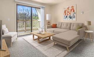 A living room with plush carpet and a slider to a balcony at Swiss Valley Apartments, Wyoming, MI
