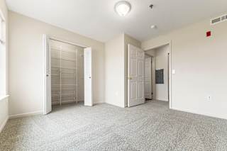 A bedroom with a carpeted floor and a walk-in closet at Tall Oaks Apartment Homes, Michigan, 49009