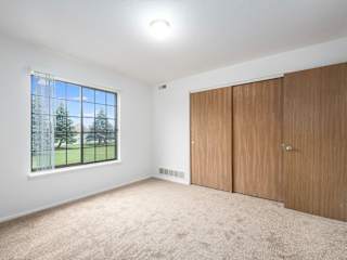 large bedroom with a window and closet doors at Tanglewood Apartments, Oak Creek, WI, 53154