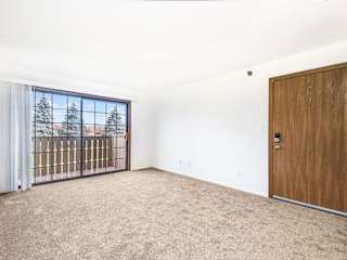 an empty living room with a slider to a balcony at Tanglewood Apartments, Oak Creek, WI, 53154