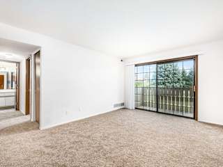 a living room with carpeting leading to a private balcony at Tanglewood Apartments, Oak Creek, WI, 53154