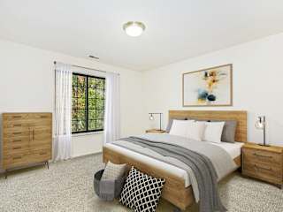 A bedroom with a bed, nightstand, and a large window at Tanglewood Apartments, Oak Creek, 53154