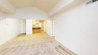 A spacious living room with a cathedral ceiling and plush carpet at Tracy Creek Apartment Homes in Perrysburg, OH