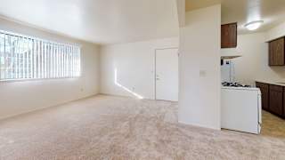 an empty living room with a large window and a view of a kitchen at Walnut Trail Apartments, Portage