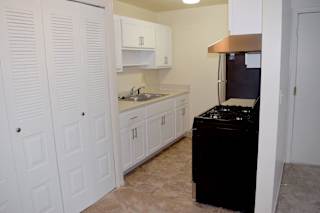 a kitchen with white cabinets and a stove and a sink at Walnut Trail Apartments, Portage