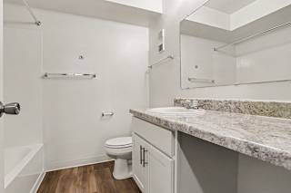 A white bathroom with a large counter top and a toilet at Walnut Trail Apartments, Michigan