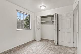 A white bedroom with a window and a closet at Walnut Trail Apartments, Michigan