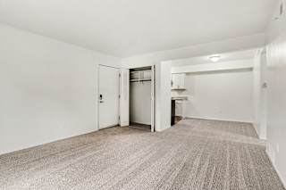A living and dining room with a carpeted floor and a closet at Walnut Trail Apartments, Michigan