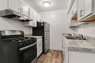 An upgraded kitchen with stainless steel appliances and white cabinets at Walnut Trail Apartments, Michigan