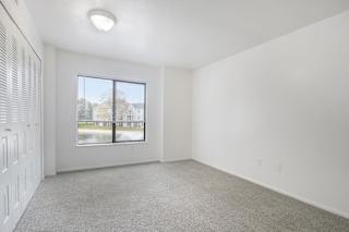 A room with a window and a carpeted floor.