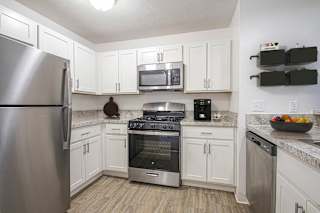A kitchen with white cabinets and a stainless steel refrigerator.