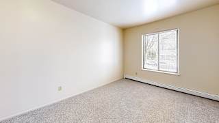 A spacious bedroom with a window and plush carpeting at Wood Creek Apartments, Kenosha, WI, 53144