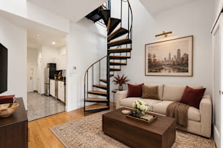 A living room with a spiral staircase and a painting on the wall.