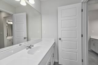 A white bathroom with a sink and mirror.