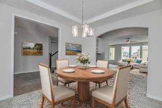 A dining room with a round wooden table surrounded by chairs.