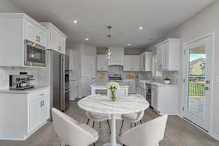 A white kitchen with a table and chairs in the middle.