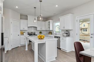 A kitchen with white cabinets and a marble table.