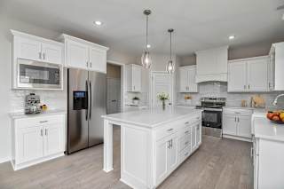 A modern kitchen with white cabinets and stainless steel appliances.