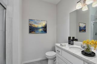 A bathroom with a toilet, sink, and a painting on the wall.