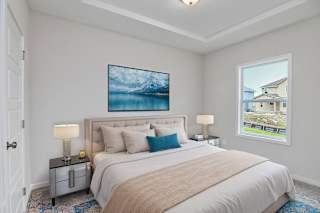A bedroom with a large bed, a painting above it, and a window showing a house.