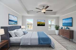 A bedroom with a bed, a dresser, and a ceiling fan.