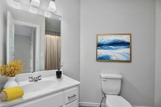 A bathroom with a white toilet and a painting of a wave on the wall.