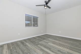 A room with a ceiling fan and a window with blinds.