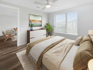 A bedroom with a large bed and a painting on the wall.