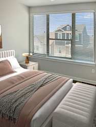 A bedroom with a large bed and a window with blinds.