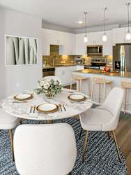 A modern dining room with a marble table and white chairs.