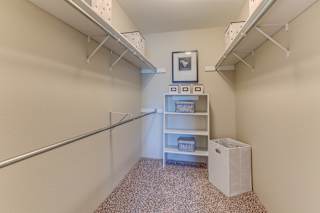 A small room with a shelf and a trash can.