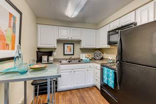 A kitchen with white cabinets and a black refrigerator.