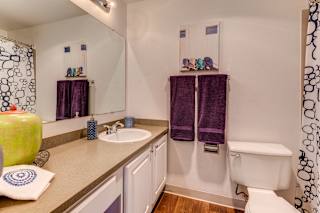 A bathroom with a white tub and purple towels.