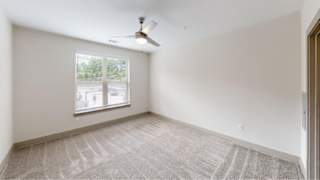 A room with a ceiling fan and a window with blinds.