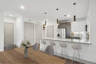 A modern kitchen with a wooden table and grey bar stools.