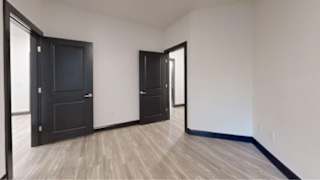 A room with a black door and a wooden floor.