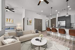 A modern living room with a beige sofa, a coffee table, and a bar area with stools.