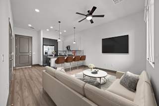A modern living room with a beige couch and a ceiling fan.