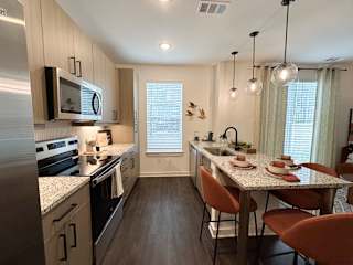 Galley kitchen with island seating and pendant lighting at The Wren Apartments, Lawrenceville