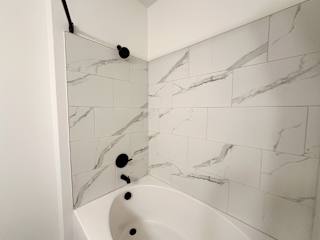 Modern bathroom with marble tile and black fixtures at The Wren Apartments, Lawrenceville