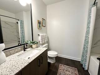 Bathroom with granite vanity and white tub at The Wren Apartments, Lawrenceville