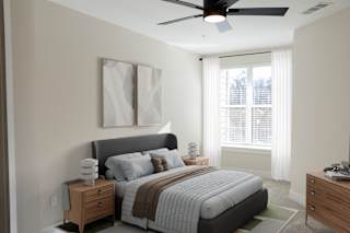 A bedroom with a large bed, a ceiling fan, and two framed pictures on the wall.at District at Riverside Apartments, Tennessee