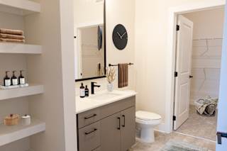A bathroom with a toilet, sink, mirror, and shelves.at Riverside Apartments, Tennessee, 37406